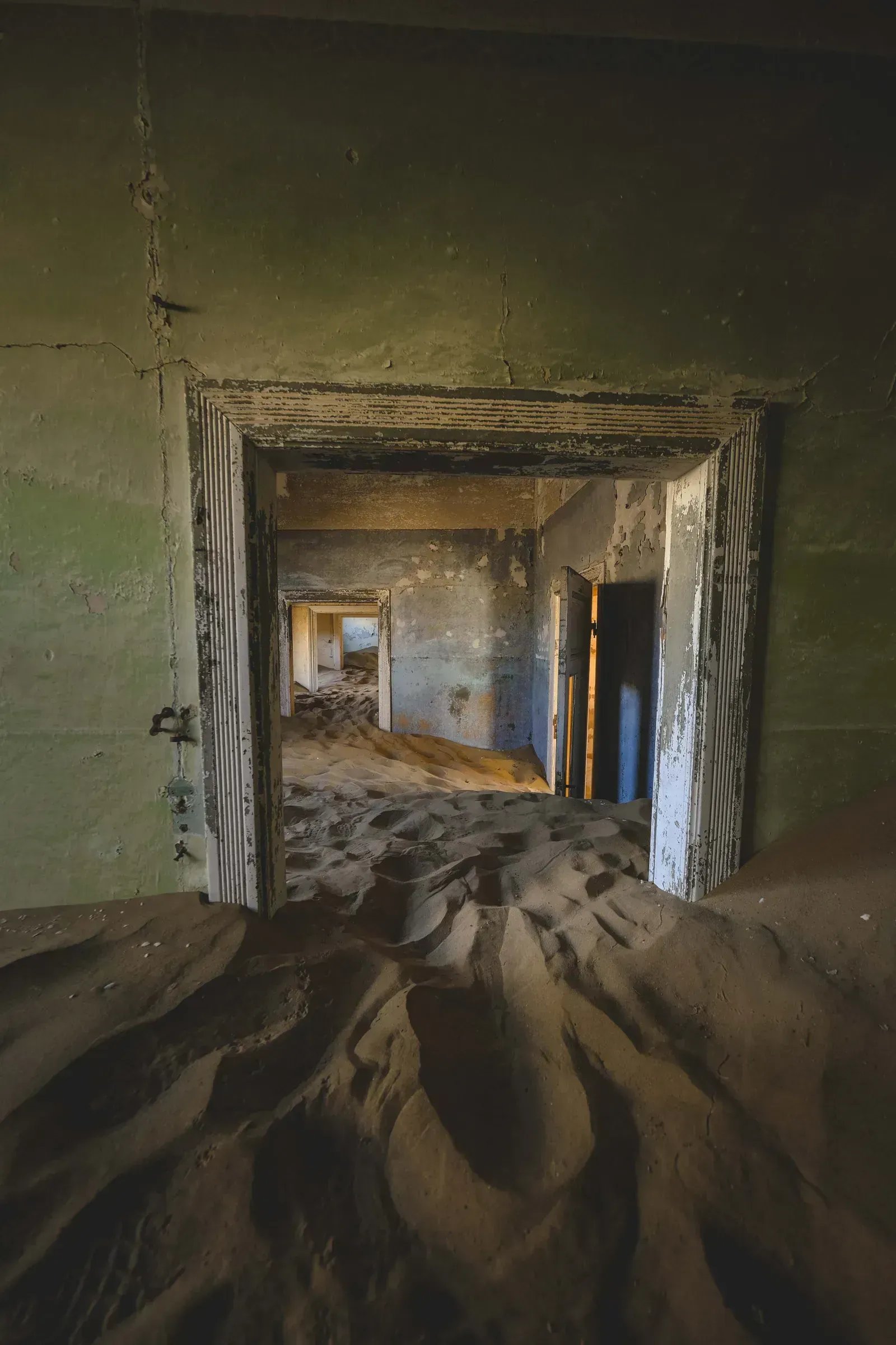 Sand drifts through the doorways of Kolmanskop's abandoned rooms