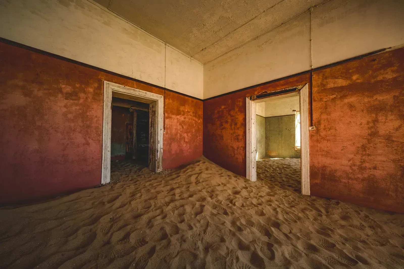 A dune of sand swallows a terracotta room at Kolmanskop