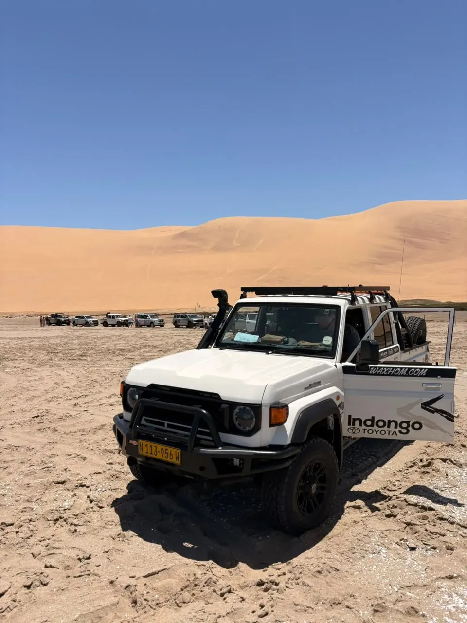The tour's Land Cruiser parked below a towering Namib dune