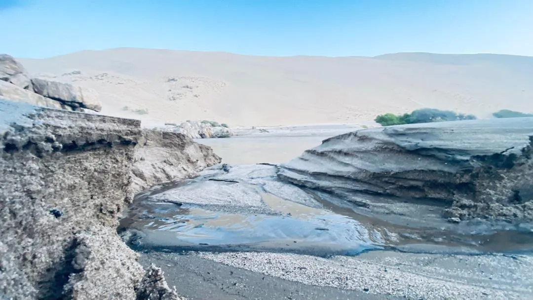 Eroded sediment banks and a pool in the dry riverbed