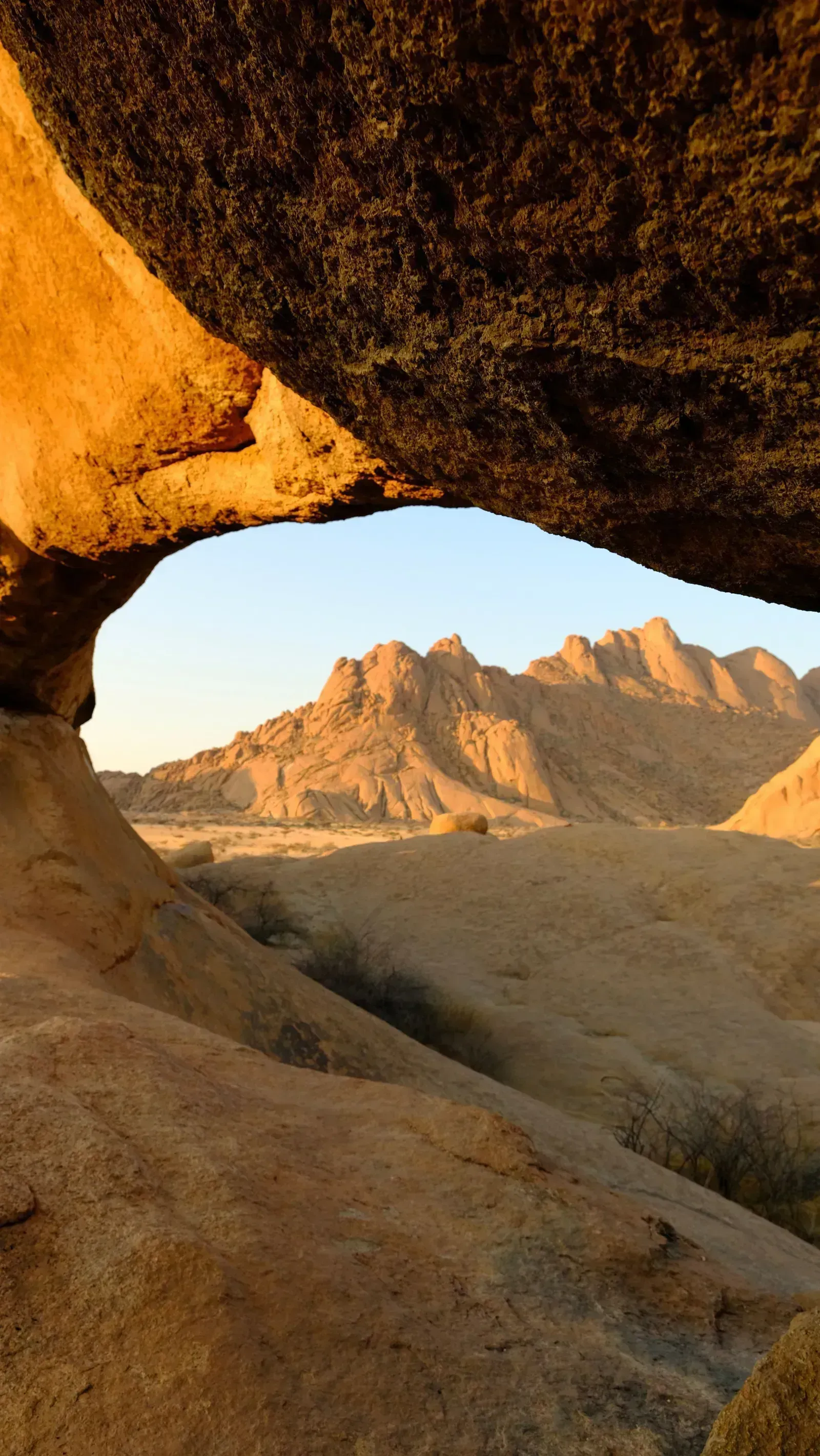 Golden light frames the peaks beneath a granite arch